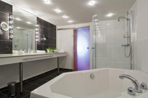 a bathroom with a tub and a shower and a sink at Ochsen Hotel & Restaurant Binzen / Basel in Binzen