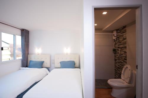 a bedroom with two beds and a toilet at Hoppers Place Donmuang in Bangkok