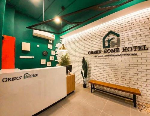 a green house hotel with a bench in a lobby at Hotel O Green Home Hotel in Sepang