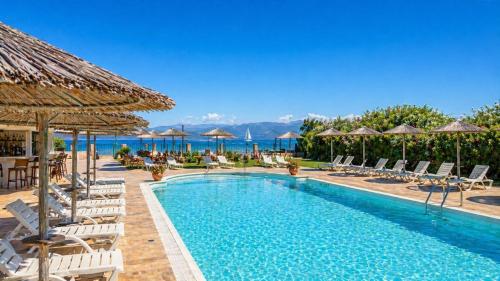 a pool at a resort with chairs and umbrellas at Koulouris Beach Hotel in Kavos