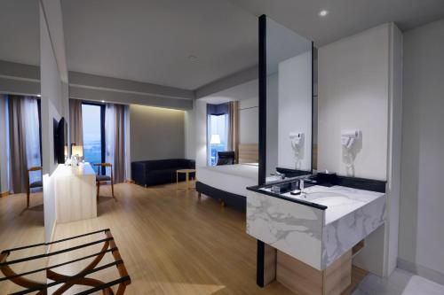 a bathroom with a sink and a bed in a room at Harper Cikarang by ASTON in Cikarang