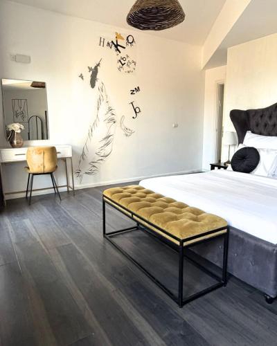 a bedroom with a bed with a bench and birds on the wall at סוויטת בית ינאי in Beit-Herut