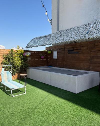 a patio with a bench and a chair on the grass at סוויטת בית ינאי in Beit-Herut