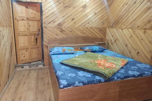 a bed in a wooden cabin with a blanket on it at Hotel priyanshu in Madheso
