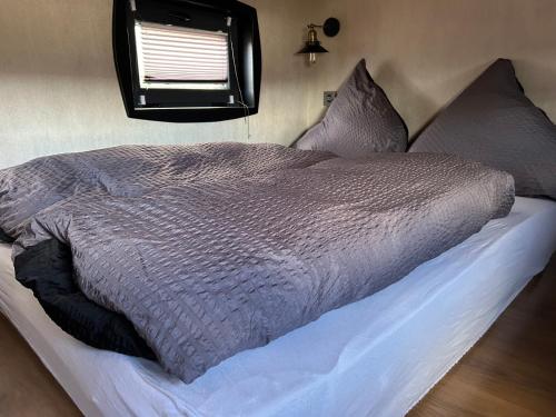ein Bett mit einer grauen Bettdecke in einem Schlafzimmer in der Unterkunft Tiny Haus Speyer in Langenselbold