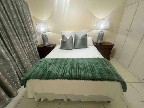 a bedroom with a bed with green sheets and pillows at Spacious 4BR Home Pool Balconies Krantzkloof in Kloof