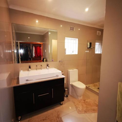 a bathroom with a sink and a toilet and a mirror at Spacious 4BR Home Pool Balconies Krantzkloof in Kloof