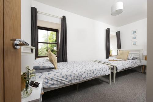 a bedroom with two beds and a window at Aval Dor Barn, Hot Tub, Pet Friendly in Ludgvan