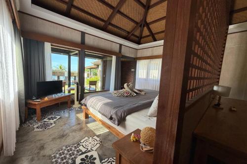 a bedroom with a bed and a television in a room at Hi Blue Bali Melasti Dive Resort in Karangasem