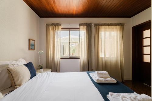 a bedroom with a large bed and a window at Casa da Areia - by RowdHouses - Private Beach Access in Praia da Barra