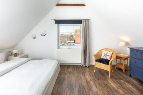 a bedroom with a bed and a chair and a window at Ant Diekskant in Juist