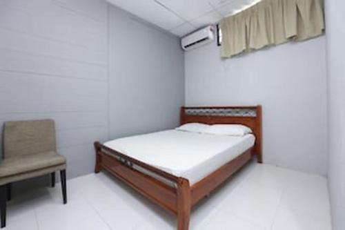 a small bedroom with a bed and a chair at Hotel O D'noor in Kota Bharu