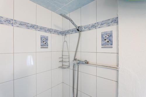 a shower in a bathroom with white tiles at La Petite Maison in Puimoisson