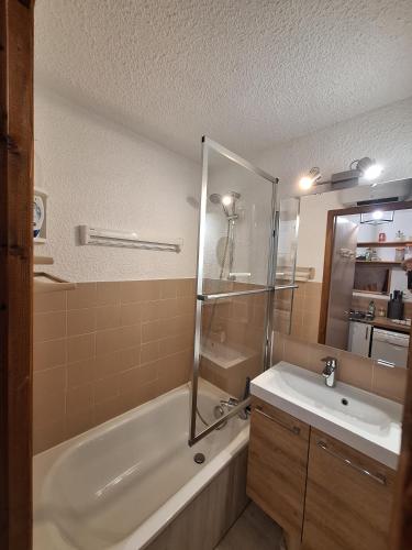 a bathroom with a tub and a sink and a shower at Duplex au calme vue montagne in Abondance