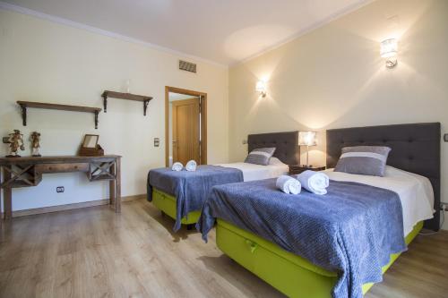 a bedroom with two beds with blue sheets and a table at Villa Valentina by Algarve Holidays in Almancil