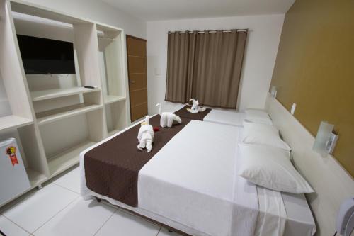 a bedroom with a large bed with two stuffed animals on it at Pousada Maragolfinho in Maragogi
