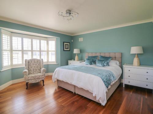 a bedroom with blue walls and a bed and a chair at Sunnyside in Riverchapel