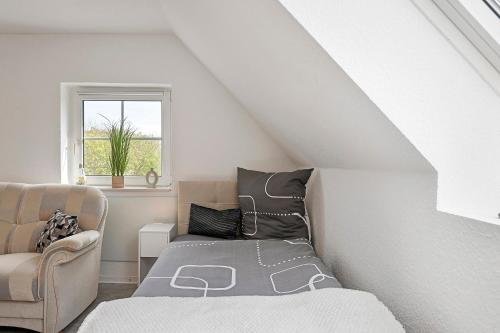 a attic bedroom with a bed and a chair at Süße kleine Wohnung in Eggstedt