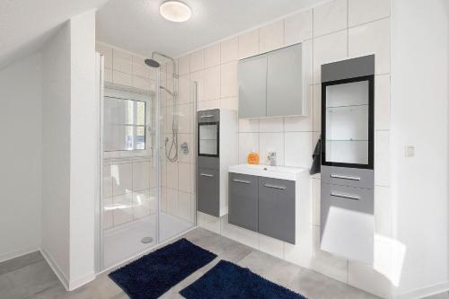 a white bathroom with a shower and a sink at Süße kleine Wohnung in Eggstedt