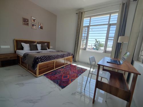 ein Schlafzimmer mit Bett, Schreibtisch und Fenster in der Unterkunft CloudHaus Bir Private 3BHK Villa Mountain Views in Bir