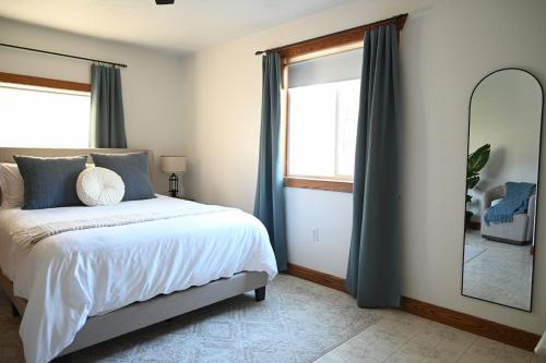 a bedroom with a bed with blue curtains and a mirror at Pondside Abode in Dundee