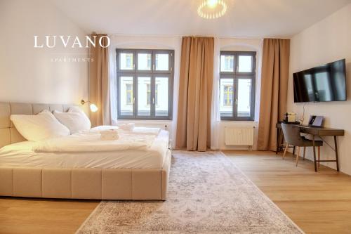 a large bedroom with a white bed and a television at Zentral & ruhig - Stadt, Elbe und Natur nebenan in Magdeburg