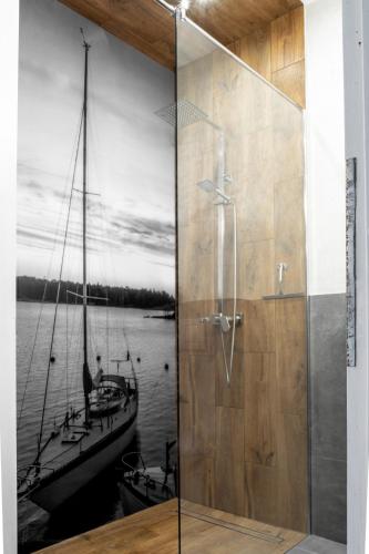 a shower with a glass door with a painting of a boat at Apartamenty Pod Kominkiem in Rydzewo