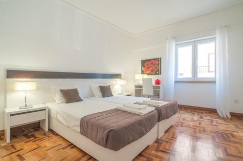 een witte slaapkamer met een groot bed en een raam bij City Center Stylish Apartment in Lissabon