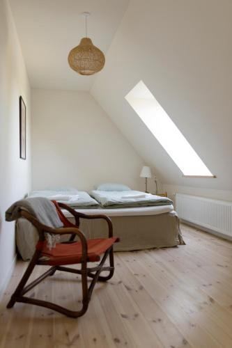 a bedroom with a bed and a chair in it at Atma Guesthouse - cozy and simple farmhouse bed & breakfast in Marstal