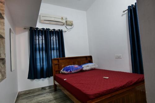 a small room with a bed with a red bedsheet at Velankanni Home Stay in Mangalore