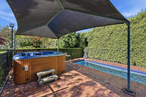 a hot tub under an umbrella next to a swimming pool at Snowline - Ultimate Getaway, Pool, Spa & Tennis in Canobolas