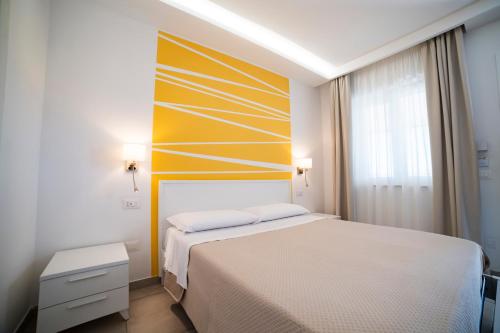 a bedroom with a white bed and a yellow wall at B&B MargAni Tropea in Tropea