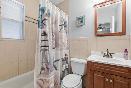 a bathroom with a shower curtain with a toilet and a sink at Flagler Suites 3 in New Smyrna Beach