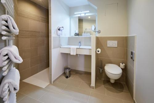 a bathroom with a toilet and a sink and a mirror at Les Villas d'Arromanches, Teritoria in Arromanches-les-Bains