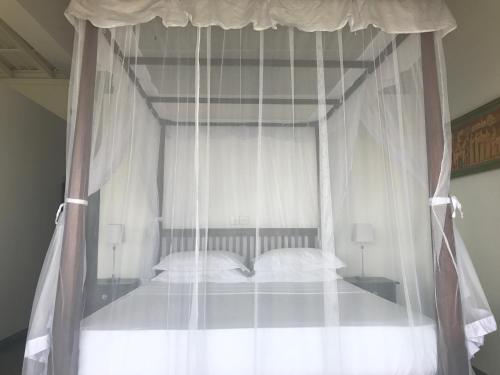 a canopy bed with white curtains and white pillows at Lara's place in Unawatuna