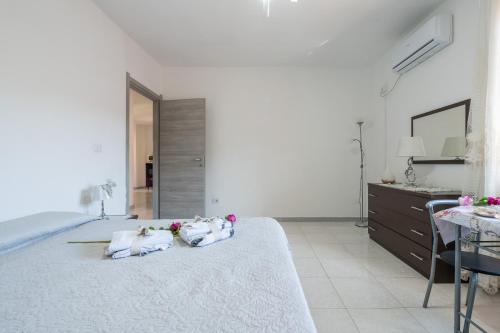 a white bedroom with a large bed with flowers on it at Piccola Casa Melis in Capoterra