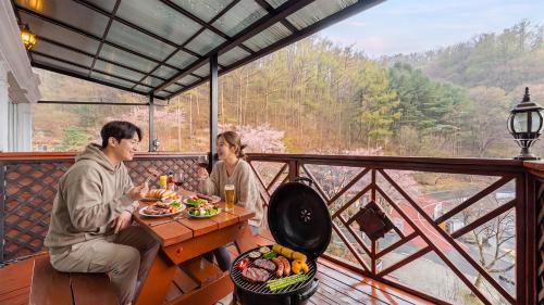 a man and a woman sitting at a table with food at Gapyeong Hue 910 Pension in Gapyeong