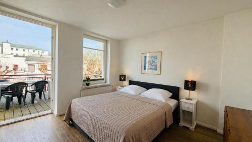 a bedroom with a bed and a large window at CBlue "Apartmenthaus Chrischanshof" in Warnemünde