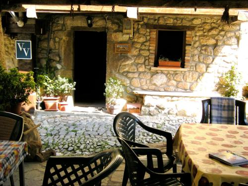 un patio con mesa y sillas y un edificio de piedra en El Horrín De Claudia, en Ponga