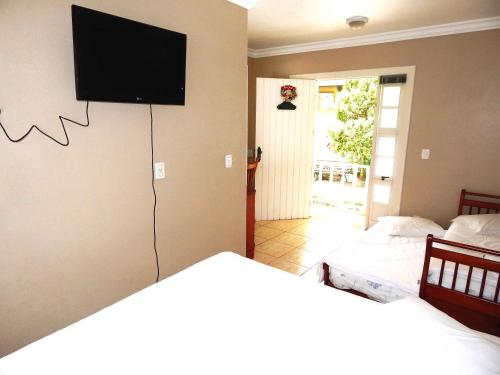 a bedroom with two beds and a flat screen tv on the wall at Apartamentos Sulla Collina Centro de Gramado localizado próximo da rua Coberta in Gramado