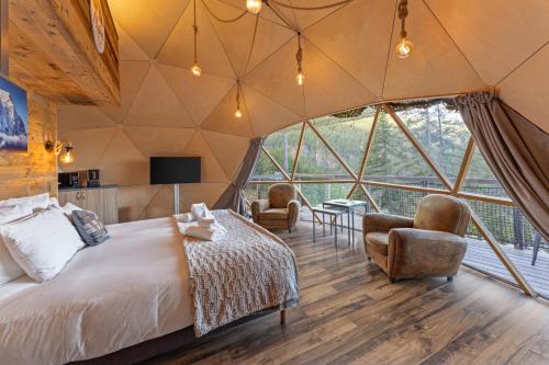 a bedroom in a tent with a bed and chairs at Alpin D'Hôme Hôtel & Spa in Les Orres