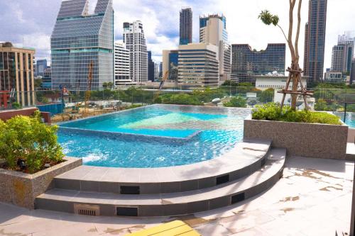 a swimming pool with a city skyline in the background at The Quart Ruamrudee by UHG in Bangkok