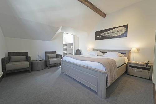 a white bedroom with a bed and a chair at Hotel des Ardennes in Corbion