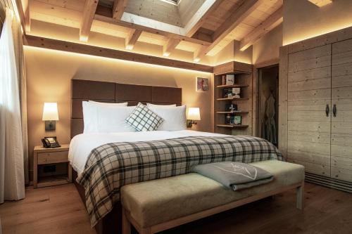 a bedroom with a bed and a bench in it at Hôtel de Rougemont & Spa in Gstaad
