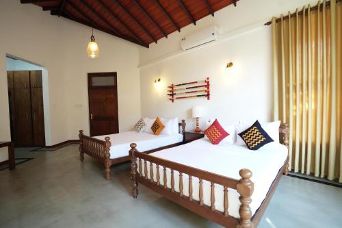 two beds in a room with white walls at Muthu Villa, Kandy in Nikawatawana