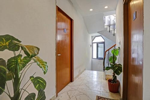 a hallway with potted plants and a wooden door at Hotel O by OYO TSA in New Delhi