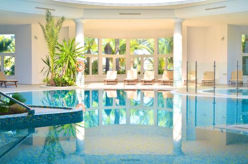 a swimming pool in a building with chairs in it at Royal Garden Palace - Families and Couples in Midoun