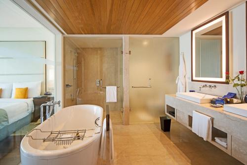 a bathroom with a tub and a shower and a bed at The Oberoi Mumbai in Mumbai