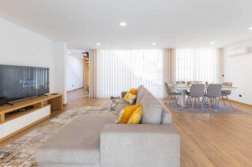 a living room with a couch and a television at Dunes Beach House with Ocean Views in Viana do Castelo
