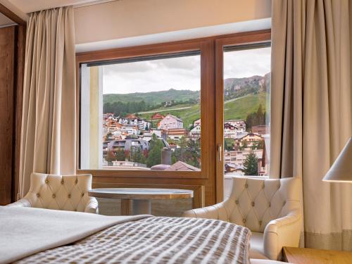 a bedroom with a bed and a large window at Hotel Arte in St. Moritz